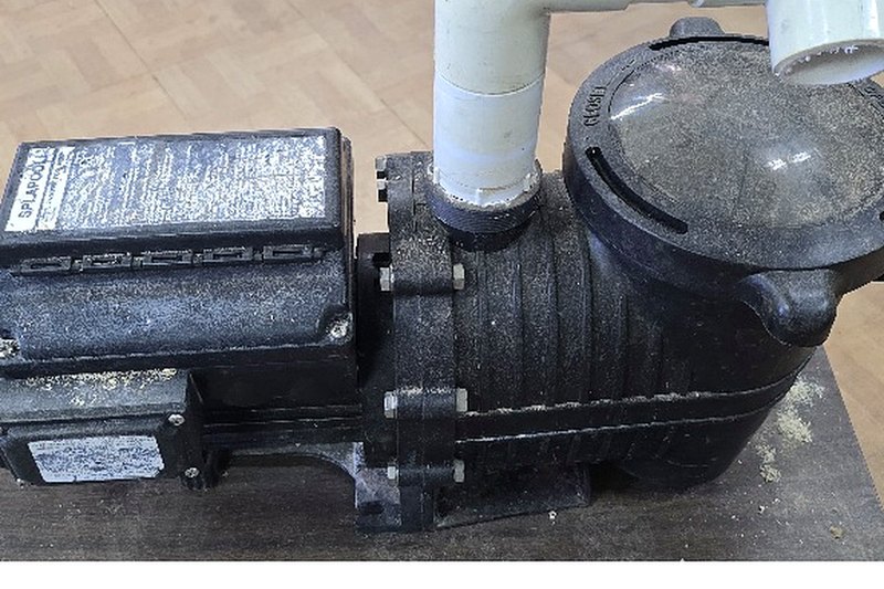 The original variable-speed pool pump before the redesign — grey industrial housing with PVC plumbing